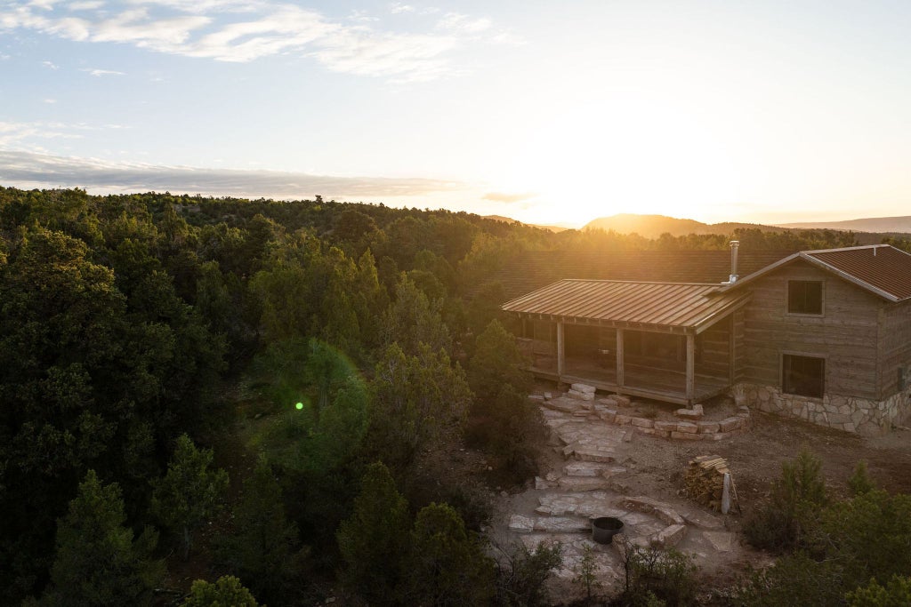 Rustic wooden lodge room with mountain views, plush bedding, and warm earth tones, featuring elegant western-inspired decor near scenic national park landscape