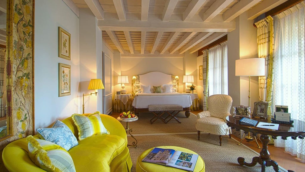 Historic Italian villa hotel with yellow facade, ornate balconies, and manicured gardens overlooking Lake Garda's tranquil waters