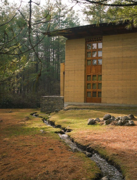 Modern luxury lodge with traditional Bhutanese architecture overlooking misty Himalayan peaks, nestled among pine forests at dusk