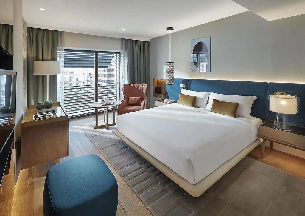 Elegant contemporary room at Mandarin Oriental Barcelona with floor-to-ceiling windows, white linens, and cream accent furnishings