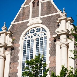 Elegant historic canal house in Amsterdam, featuring ornate facade, large windows, and classic Dutch architectural design along a picturesque waterway