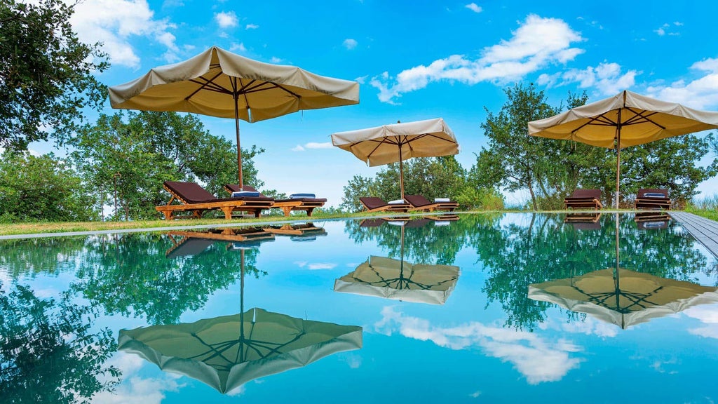 Elegant pool suite at Monaci delle Terre Nere, featuring infinity pool overlooking lush Sicilian landscape with Mount Etna in background.