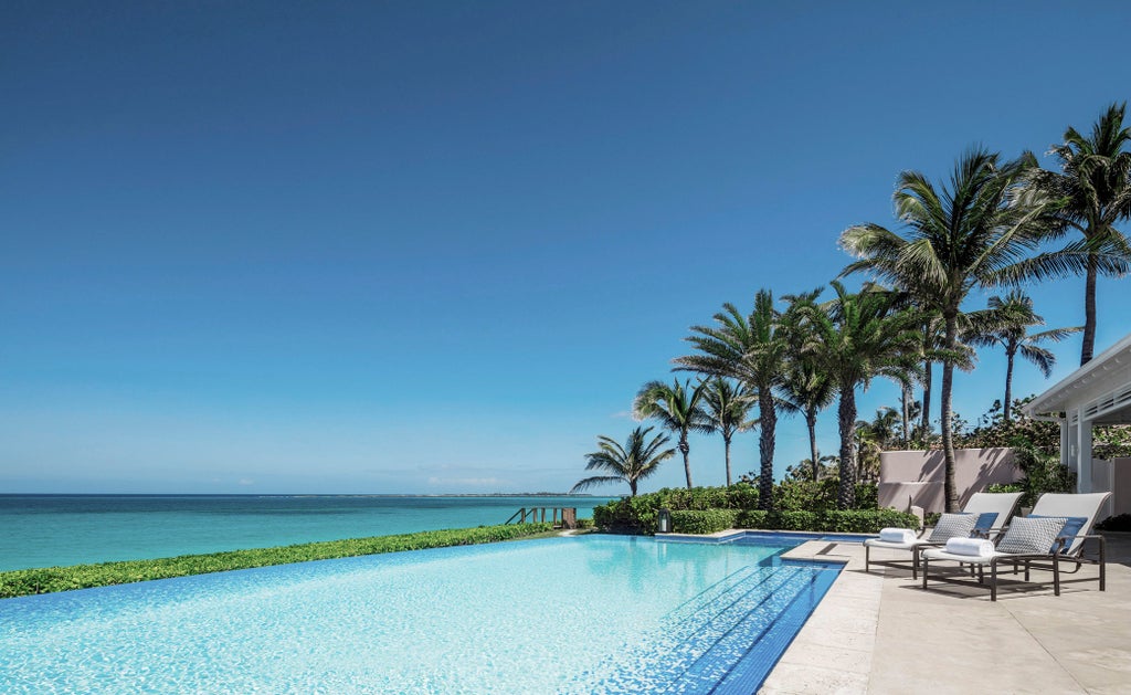 Luxurious beachfront Four Seasons resort with infinity pools overlooking turquoise Caribbean waters, surrounded by palm trees at sunset