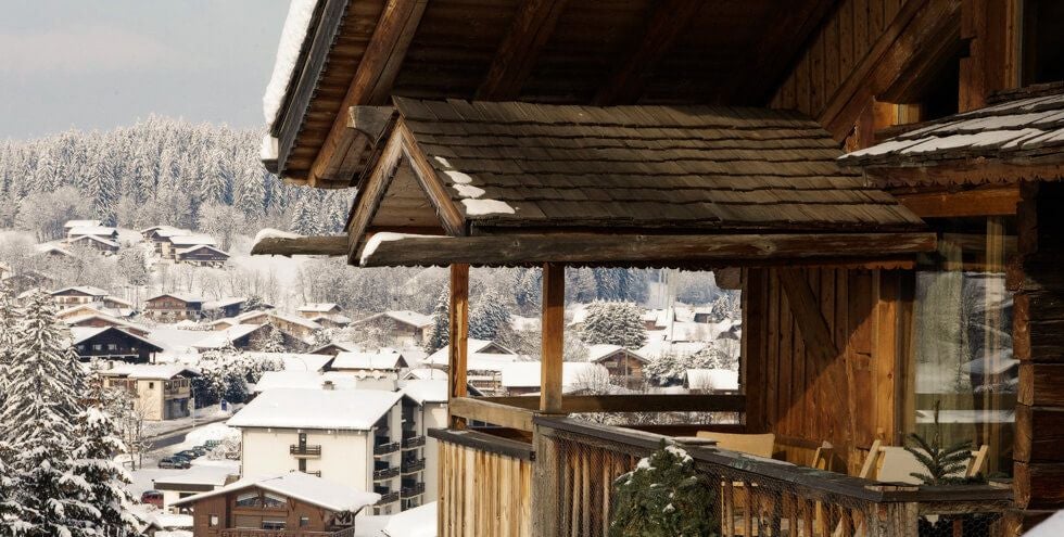 Luxurious alpine suite with warm wooden interiors, plush white bedding, and expansive mountain view, showcasing elegant French mountain lodge design