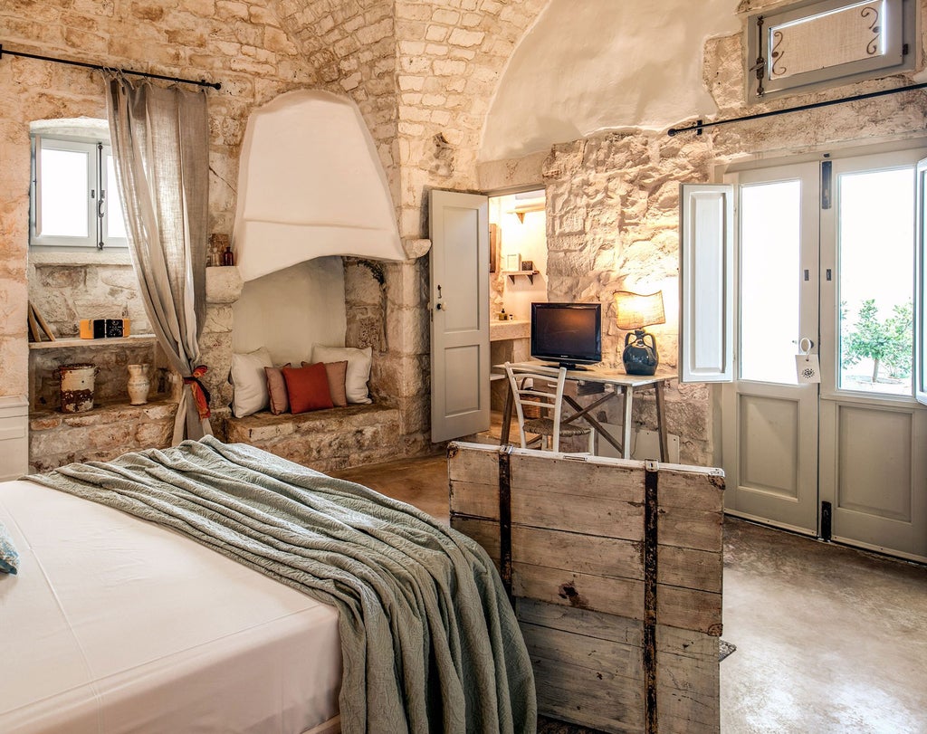 Rustic-chic superior room at Masseria Cervarolo, featuring stone walls, elegant wooden furnishings, and soft natural light in a Puglian countryside setting.