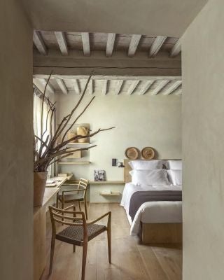 Elegant Tuscan-style junior suite with rustic wooden furniture, soft neutral tones, and panoramic countryside views at Badia di Pomaio in Italy