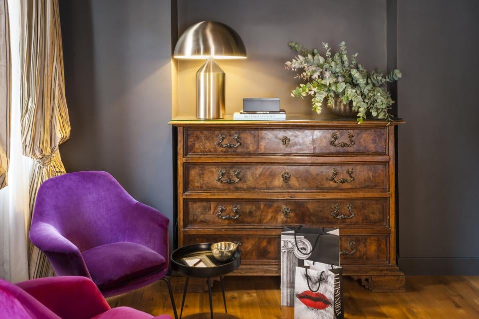 Elegant boutique hotel room in Rome featuring ornate gold mirrors, crystal chandelier, antique furnishings and high vaulted ceilings