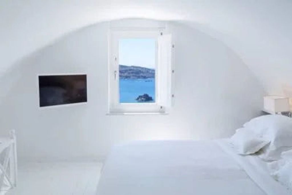 Elegant white cycladic suite with private infinity pool overlooking Santorini's caldera and Aegean Sea at golden sunset