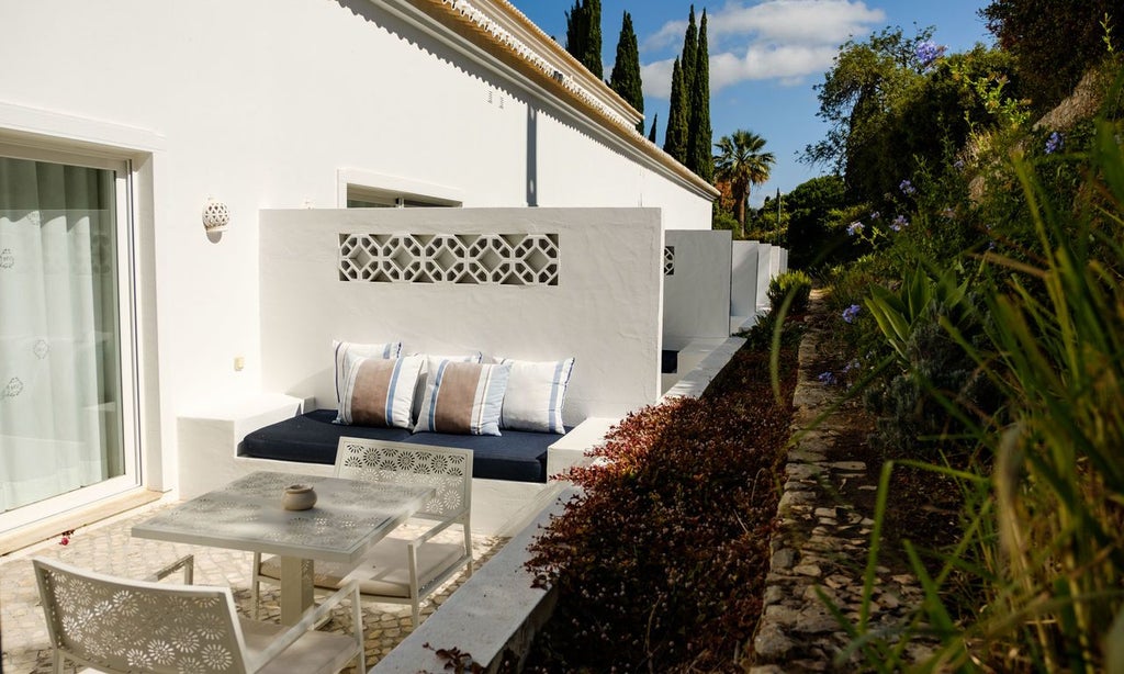 Elegant whitewashed Portuguese-style superior room with minimalist design, soft neutral tones, and natural light streaming through large windows at Octant Vila Monte.