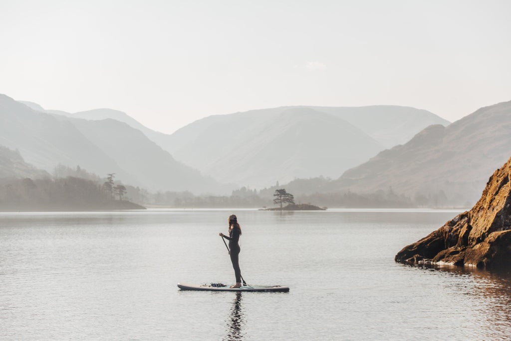 Elegant stone manor hotel nestled in lush Lake District landscape, featuring classic British architecture with manicured gardens and inviting entrance