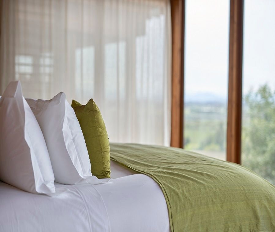 Elegant wood-paneled suite with panoramic vineyard view, featuring modern minimalist design and floor-to-ceiling windows at Clos Apalta Residence in Chile's wine country