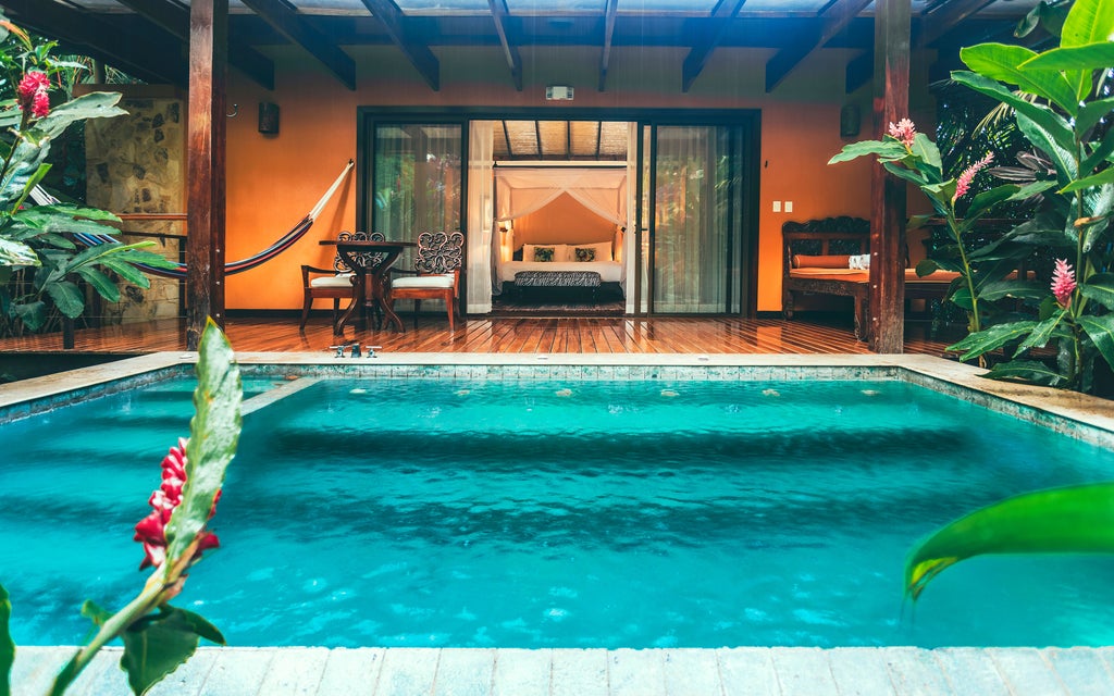 Private plunge pool surrounded by lush rainforest with rustic-luxury villa featuring wooden deck and tropical landscaping at Nayara Springs