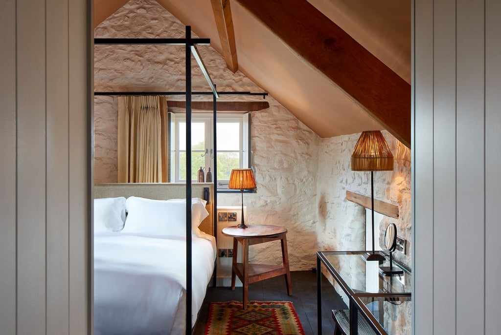 Elegant, rustic-chic bedroom with soft neutral tones, featuring a plush bed, wooden headboard, and sophisticated country-style decor at Grove of Narberth's Byre suite.