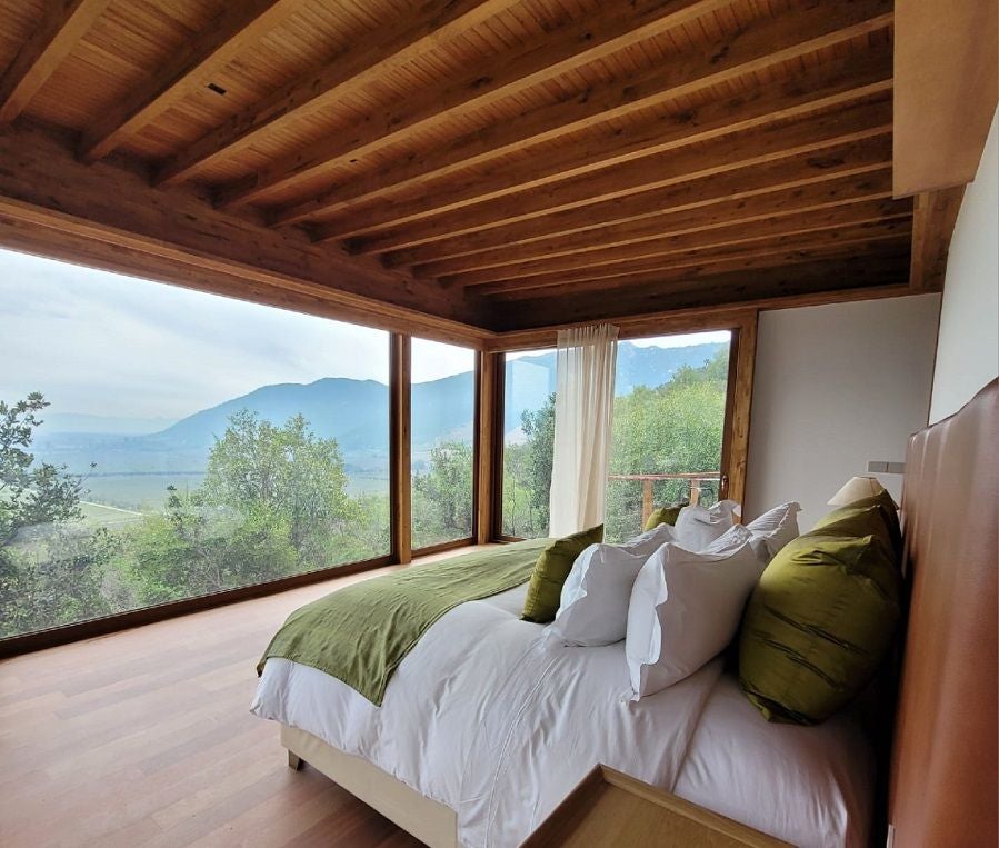 Elegant wine country suite at Clos Apalta Residence, featuring panoramic vineyard views, modern minimalist design, and plush bedding in neutral tones