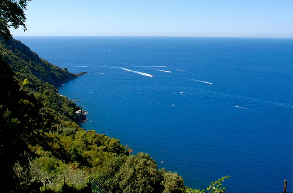 Elegant Italian villa with stone facade, lush rosemary gardens, and azure Mediterranean backdrop, showcasing refined coastal luxury in Liguria