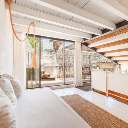 Elegant rustic Italian bedroom with stone walls, wooden furnishings, and soft natural light illuminating a charming minimalist design at Casa Talía boutique hotel