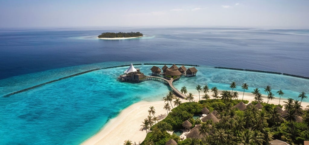 Luxurious overwater villa with private infinity pool overlooking turquoise Maldivian lagoon, surrounded by swaying palm trees