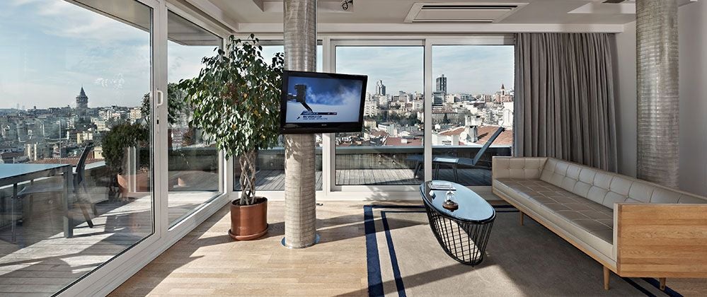 Luxurious penthouse suite at Witt Istanbul Hotel with panoramic city views, modern minimalist decor, and floor-to-ceiling windows overlooking urban landscape