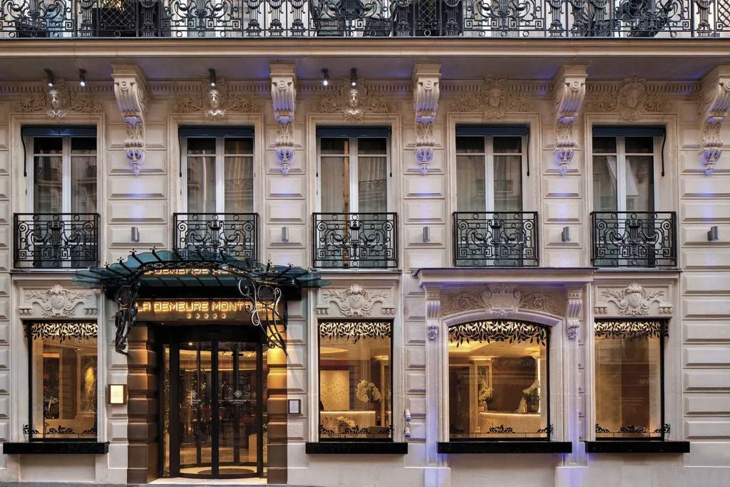 Elegant Parisian townhouse with classic Haussmann architecture, white stone facade, ornate balconies, and a grand entrance draped in luxury