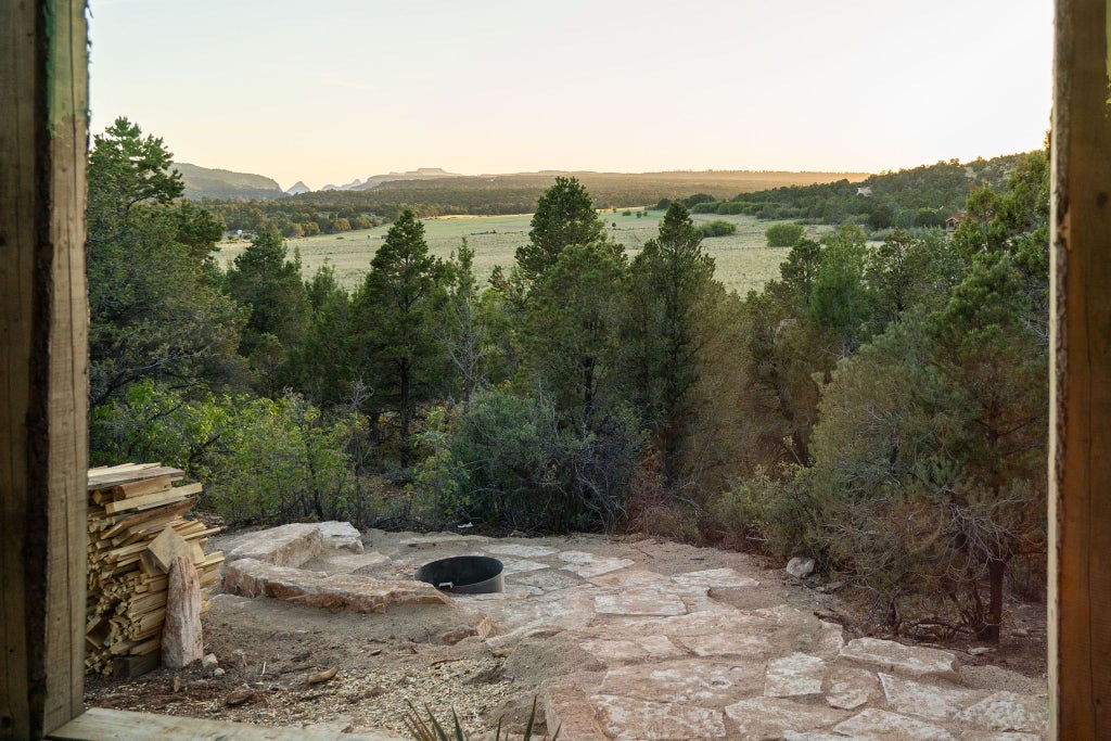 Rustic lodge room with warm wooden furnishings, plush bedding, and panoramic mountain vista at scenic ranch accommodation in western landscape