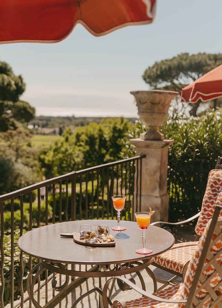 Elegant white luxury villa with blue shutters nestled in lush Mediterranean garden, Saint-Tropez coastal landscape in soft golden sunlight