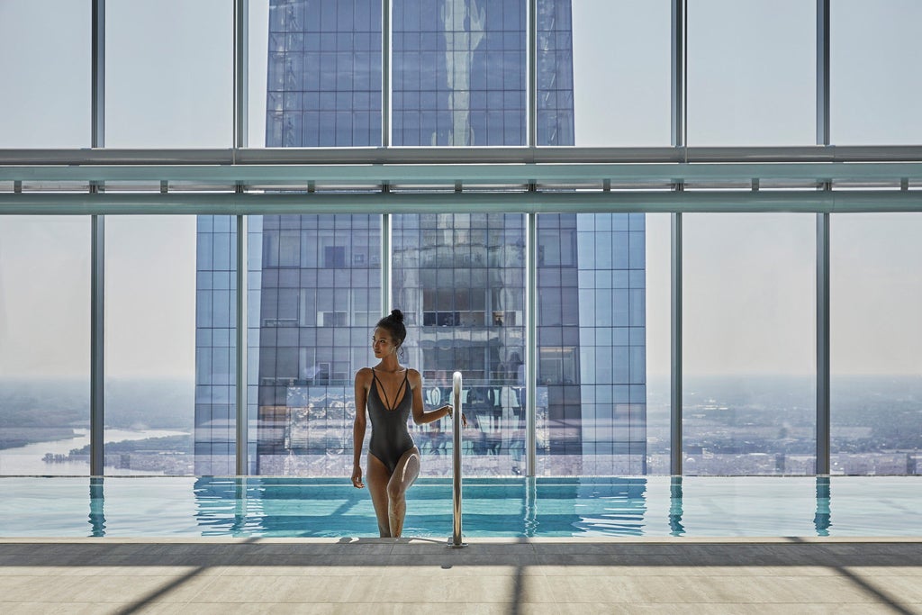 Sleek glass skyscraper hotel with Four Seasons branding rises dramatically above Philadelphia skyline, reflecting golden sunset light