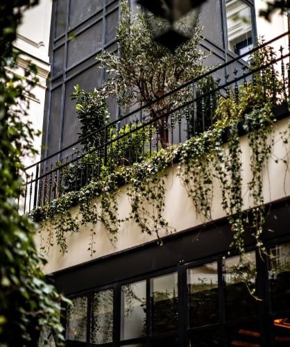 Elegant Parisian boutique hotel facade with Art Deco-inspired architecture, soft limestone exterior, ornate balconies, and luxurious contemporary styling