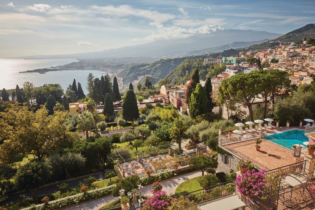 Elegant Mediterranean hotel with stone terraces overlooking Mount Etna, featuring lush gardens and classical Italian architecture