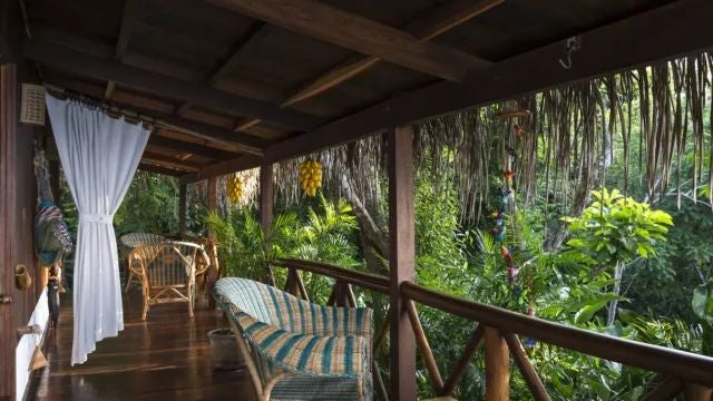 Elegant rustic bedroom with wooden furnishings, woven textiles, and large windows overlooking lush Argentine landscape at Jardin Escondido - La Lancha retreat