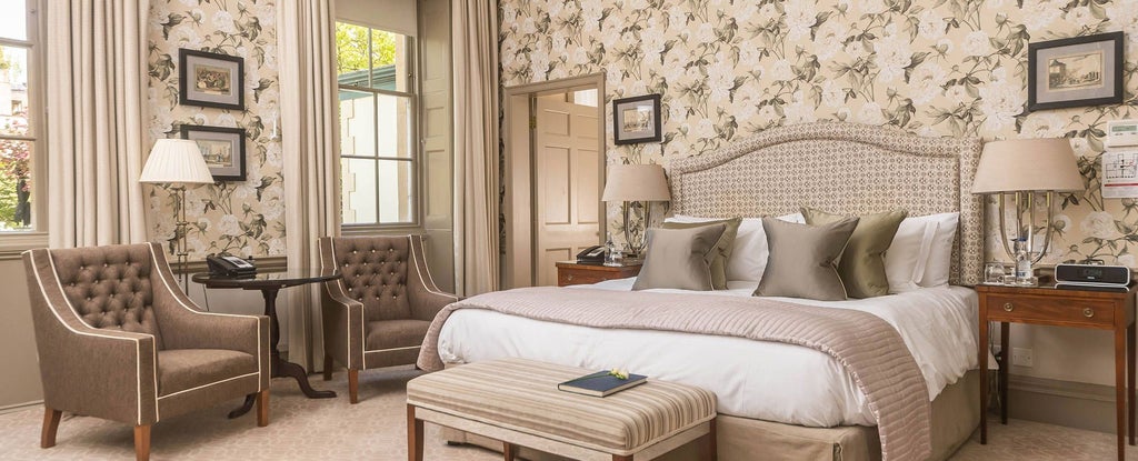 Elegant Georgian-style heritage room with soft cream walls, antique furnishings, plush king-sized bed, and ornate period details at luxury UK hotel