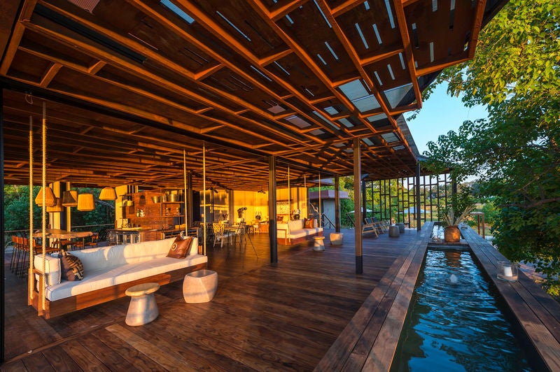 Modern safari lodge with raised wooden deck overlooking vast wetlands, featuring infinity pool and luxurious outdoor lounge area