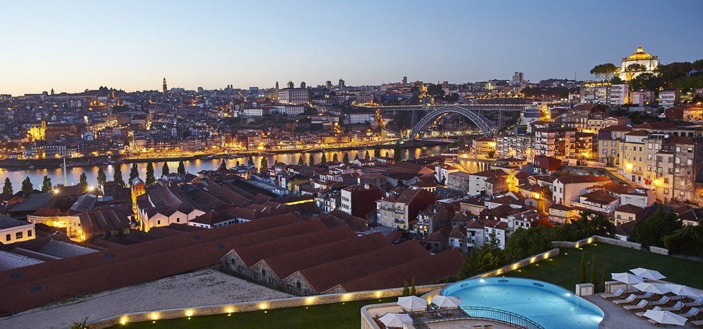 Terraced luxury hotel overlooking Porto city and Douro River, featuring infinity pool and classic Portuguese architecture at sunset