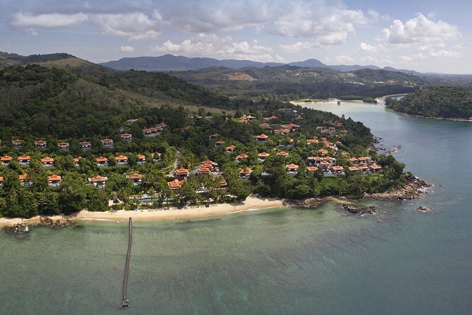 Luxurious oceanfront villa with private infinity pool overlooking Andaman Sea, surrounded by lush tropical gardens at sunset