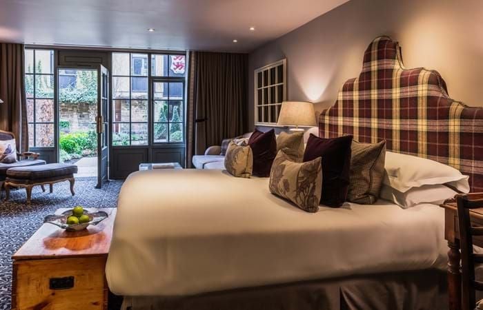 Elegant accessible hotel room with classic British decor, featuring a plush bed, wooden furnishings, and soft neutral tones in a courtyard-facing setting at The Lygon Arms