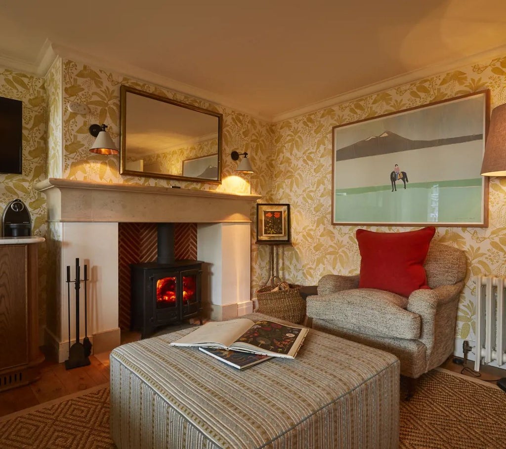 Luxurious forest hideaway suite with elegant wood paneling, plush green armchair, and expansive window overlooking lush woodland scenery at Lime Wood Hotel, UK.