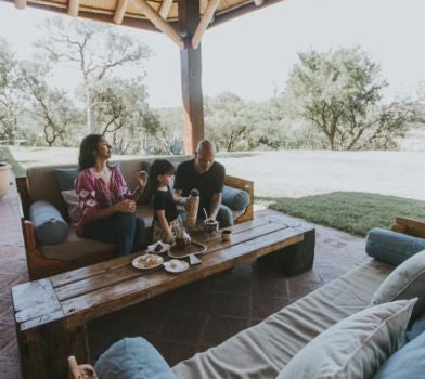 Luxurious Argentine villa suite with rustic wooden furnishings, elegant white linens, and panoramic countryside views through large windows