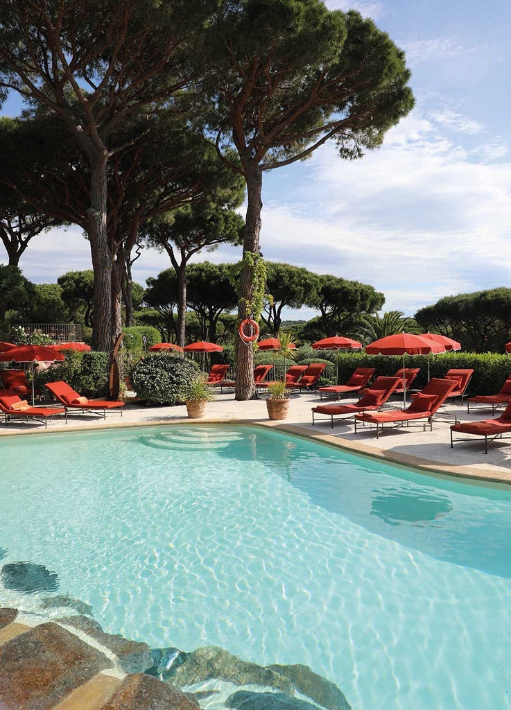 Luxurious French Riviera villa with white-washed walls, blue shutters, lush tropical gardens, and elegant Mediterranean-style architecture in Saint-Tropez