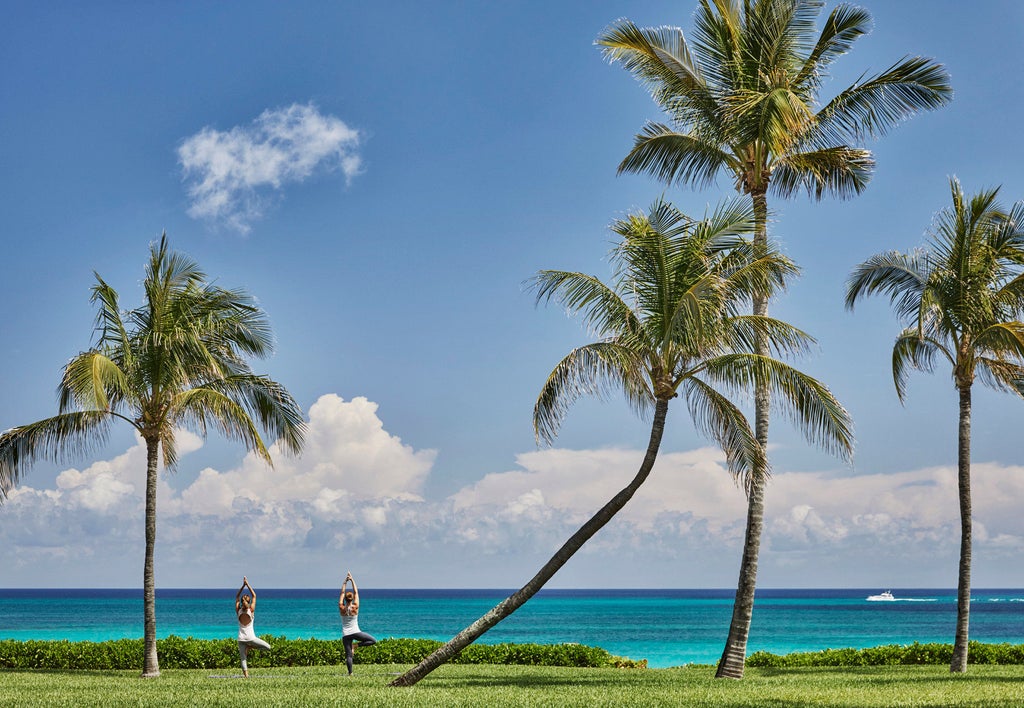 Ocean-view luxury resort with white marble columns, palm-lined infinity pool overlooking turquoise Caribbean waters and private beach cabanas