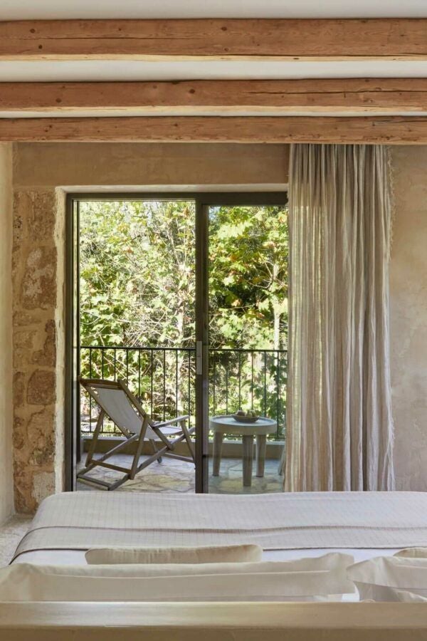 Minimalist luxury hotel room with clean design, wooden accents, white linens, and partial sea view, showcasing serene coastal retreat in Kefalonia, Greece