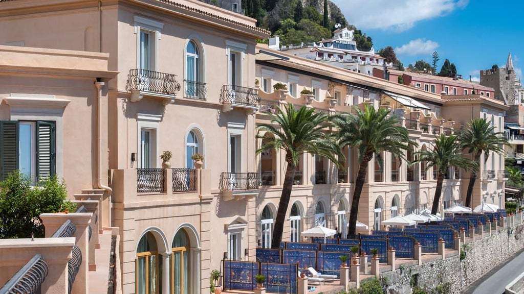 Cliffside luxury hotel with infinity pool overlooking Mount Etna and Ionian Sea, framed by classical Italian architecture at sunset