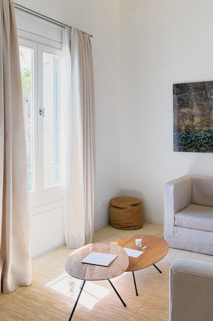 Elegant stone-walled hotel room with panoramic Mediterranean sea view, minimalist white decor, and rustic Menorca architectural charm at Torralbenc resort