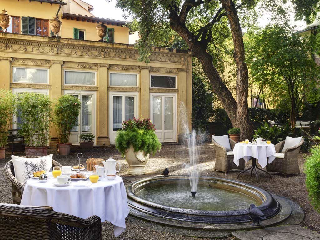 Elegant historic Palazzo di Camugliano in Tuscany, with ornate frescoed interiors, antique furnishings, and soft natural light streaming through grand windows