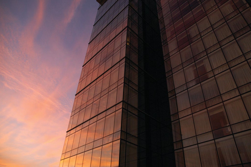 Modern 45-story glass tower Four Seasons hotel overlooking Baltimore Inner Harbor at sunset, with sleek facade and waterfront promenade