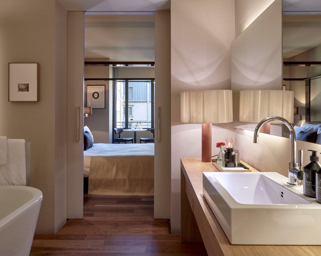 Luxurious modern Spanish hotel suite with sleek minimalist design, warm wood tones, city view, and elegant contemporary furnishings at Sir Victor hotel