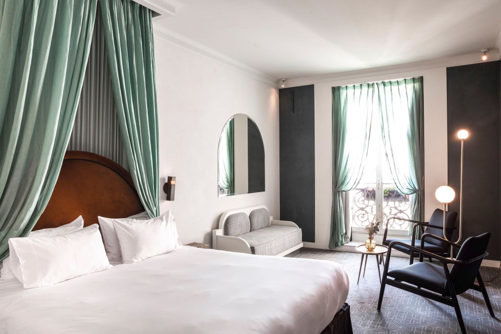 Elegant Parisian hotel room with ornate golden headboard, plush white linens, vintage crystal chandelier, and soft ambient lighting in neutral tones