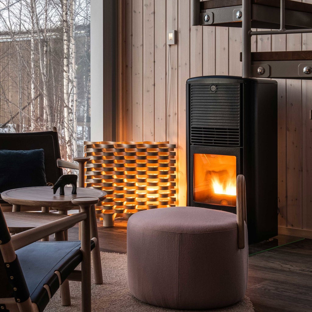 Luxurious circular wooden hotel suspended over frozen river in winter, surrounded by snow-covered pine trees in northern Scandinavian landscape