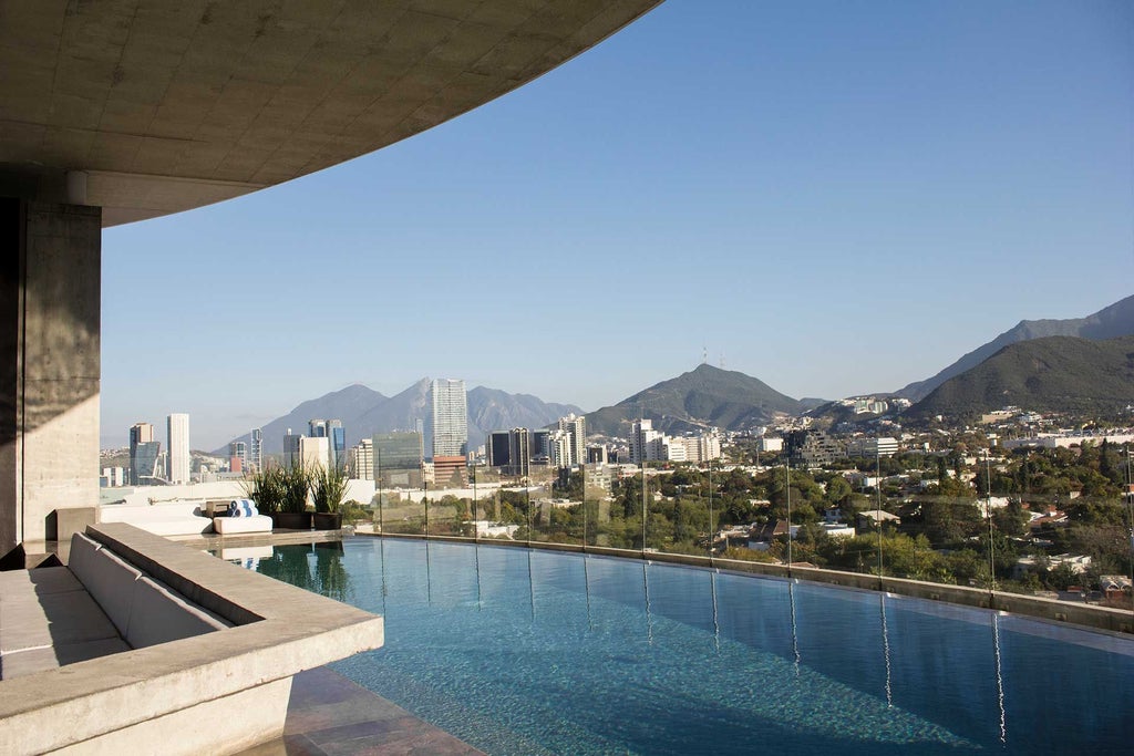 Modern minimalist hotel exterior with sleek glass facade, reflecting surrounding urban landscape of monterrey, mexico, showcasing contemporary architectural design at dusk