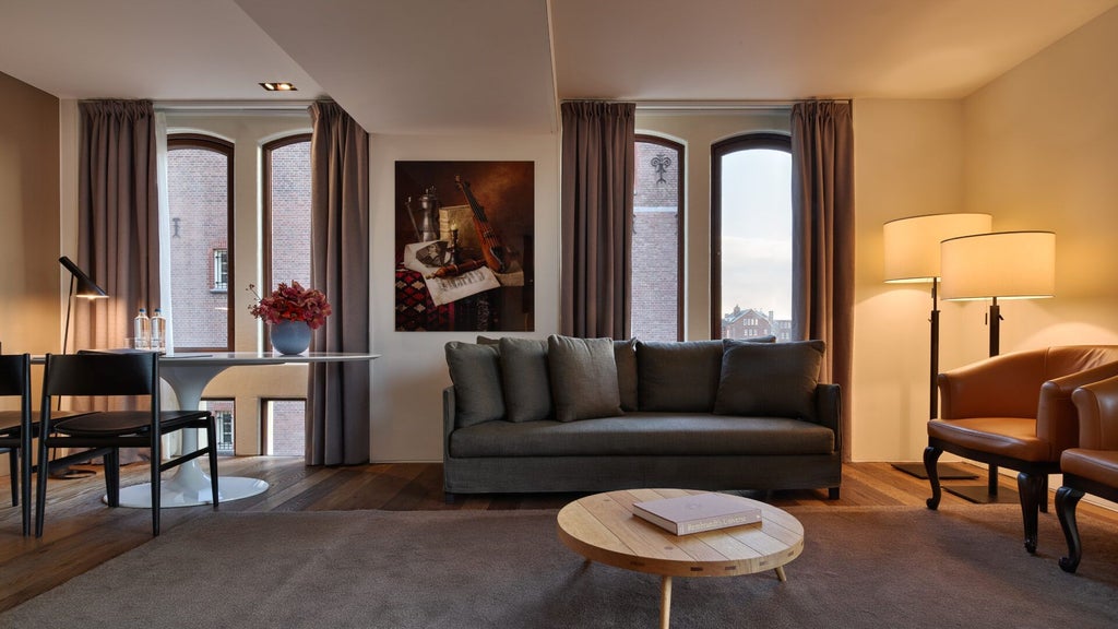 Elegant Grand Junior Suite with sophisticated design, warm wooden accents, minimalist furnishings, and expansive city view in Conservatorium Hotel, Amsterdam