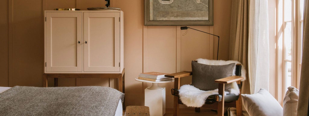 Elegant, spacious guest room at Heckfield Place with soft neutral tones, plush bedding, contemporary furniture, and natural light streaming through large windows.