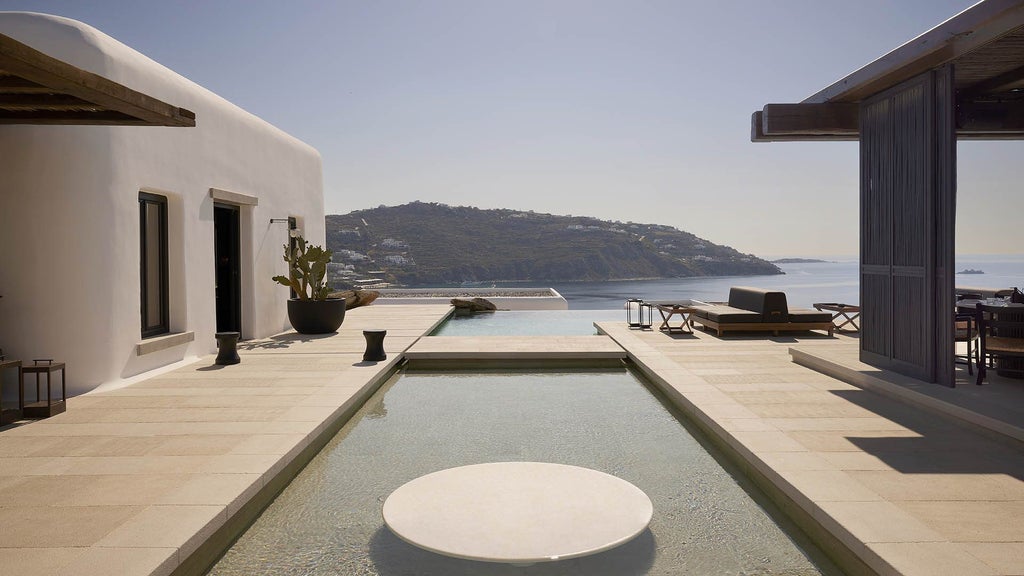 Luxurious whitewashed Greek villa with private infinity pool overlooking Mykonos bay, featuring traditional Cycladic architecture